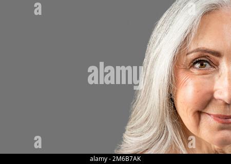 Lächelnde ältere europäische Frau nach Anti-Aging-Behandlung, schauen Sie in die Kamera, isoliert auf grauem Hintergrund, Studio Stockfoto