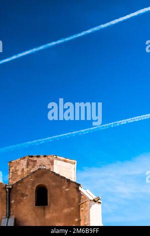 Flugstrecken über dem alten Lagerhaus in blauem Himmel Stockfoto