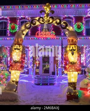 Blechsoldaten bewachen den Eingang zu einem wunderschön beleuchteten Weihnachtshaus und begrüßen frohe Weihnachten an einem Winterabend in St. Croix Falls WI. Stockfoto