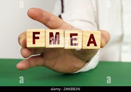 In der Hand des Mannes sind Würfel mit der Inschrift FMEA. Stockfoto