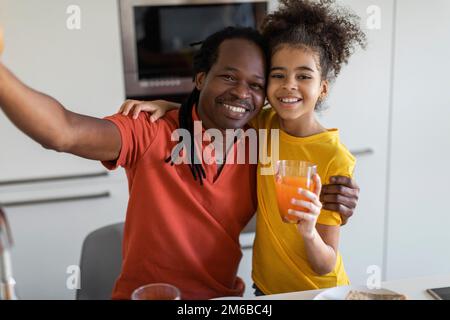 Glücklicher Schwarzer Vater Und Tochter, Die Selfie In Kitchen Zum Mittagessen Mitnehmen Stockfoto