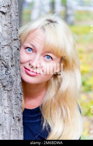Blonde Frau mit Baumhintergrund Stockfoto