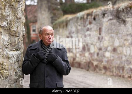 Älterer Mann an der Stadtmauer einer historischen deutschen Stadt Stockfoto