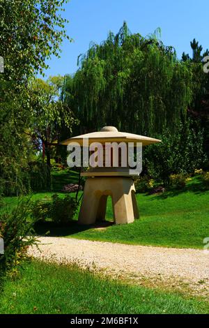 An einem sonnigen Sommertag befindet sich ein kleiner Wachturm aus Beton im Park in der Nähe von Fußwegen mit Bäumen und Gras Stockfoto