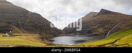 Panoramablick auf die Saksun-Gezeitenlagune mit grünen Feldern und der mit Rasen überdachten Kirche Stockfoto