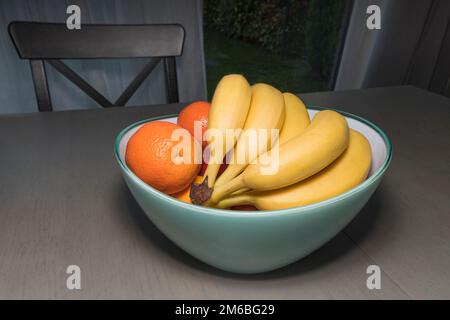 Bananen und Orangen in einer Vase auf dem Tisch Stockfoto