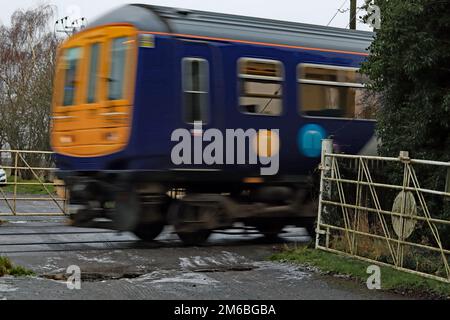 Ein Gesundheits- und Sicherheitsproblem und eine gefährliche Situation, wenn ein Zug über einen Bahnübergang fährt, an dem die Tore für den Straßenverkehr offen gelassen wurden. Stockfoto