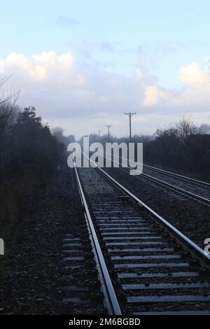 Am zweiten Weihnachtsfeiertag 2022, wenn keine Züge auf der ländlichen Eisenbahnlinie von Wigan nach Southport verkehren, sind die Schienen leer und sehen steingrau aus Stockfoto