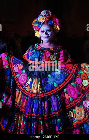 Eine Frau, die traditionell gesticktes mexikanisches Folk-Kleid und geblümten Kopfschmuck für die Catrina Parade, Teil von Day of the Dead, Merida, Mexiko trägt Stockfoto