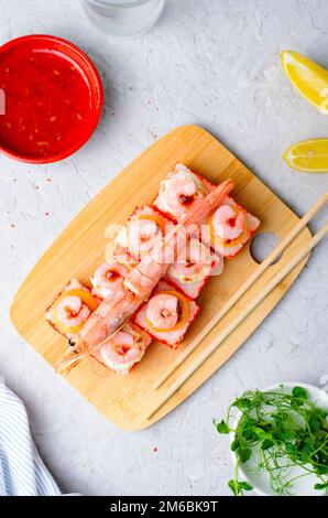 Sushi Rolls mit Langoustine und Shrimps, gebackene Sushi Rolls Seafood and Crab, Sahnekäse auf hellem Hintergrund Stockfoto