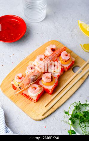 Sushi Rolls mit Langoustine und Shrimps, gebackene Sushi Rolls Seafood and Crab, Sahnekäse auf hellem Hintergrund Stockfoto