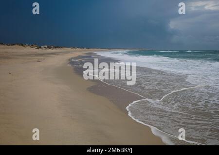 Praia da Barra, Ilhavo, Portugal - Küste, Küste, Küste des Atlantischen Ozeans. Strand, dunkelblauer stürmischer Himmel und Wolken. Bewölktes Wetter und welliges Meer Stockfoto
