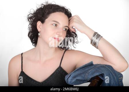Junge Modell in ihrer Mitte der 20er Jahre saß auf einem holzstuhl mit einer blauen Jeans Jacke. Stockfoto