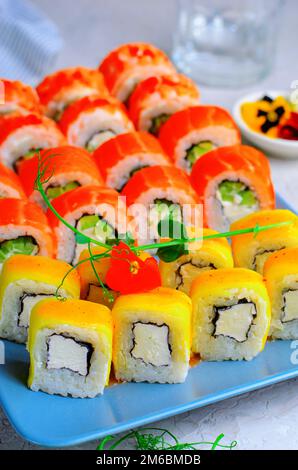 Sushi-Brötchen mit Lachs, Garnelen und Mango auf hellblauem Hintergrund, japanische Küche, asiatische Küche Stockfoto