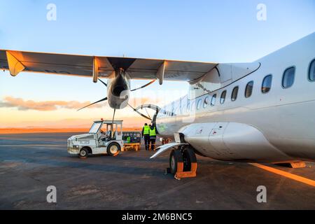 Gepäck in der Tagesanbruch im Flugzeug laden Stockfoto