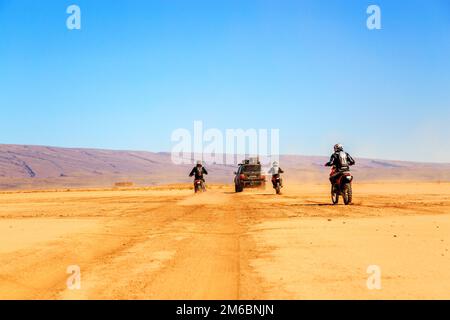 Merzouga, Marokko - Februar 22 2016: Konvoi von Geländefahrzeugen (4x4 und Motorräder) in der marokkanischen Wüste bei Merzouga. Merzouga ist f Stockfoto