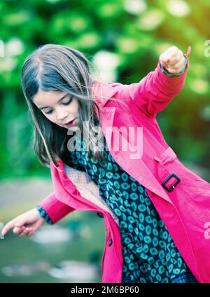 Hübsches kleines Mädchen, das auf die Felsen am Ufer springt Stockfoto