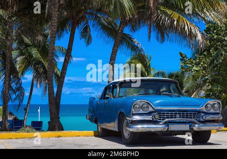 Amerikanisch-blauer Oldtimer am Strand unter Palmen in Varadero Kuba Stockfoto