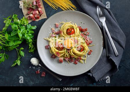 Herzhafte Spaghetti im südtiroler Stil mit Speck, Eigelb und Kirschtomaten Stockfoto