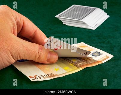 Die Hand des Mannes hebt die zwei Karten, die einem Poker ausgehändigt wurden Stockfoto