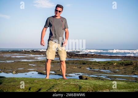 Man on Rocks am Meer Stockfoto
