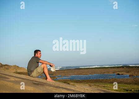 Man on Rocks mit Buch und Musik Stockfoto