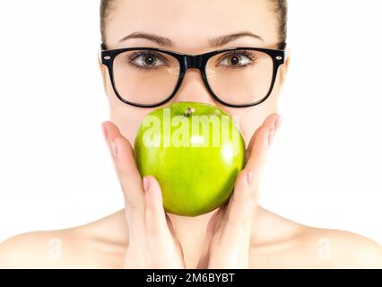 Porträt einer schönen jungen Frau in Brille mit grünem Apfel in der Hand vor weißem Hintergrund Stockfoto