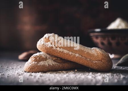 Nahaufnahme der französischen Kekse namens „Biscuit à la Cuillère“ auf dunklem Holzhintergrund. Traditionelles Konzept Stockfoto