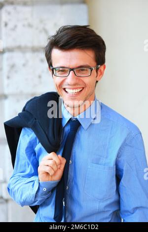 Erfolgreiche hübscher junger Geschäftsmann eine Brille und stand in der Nähe des Gebäudes glücklich lächelnd Stockfoto