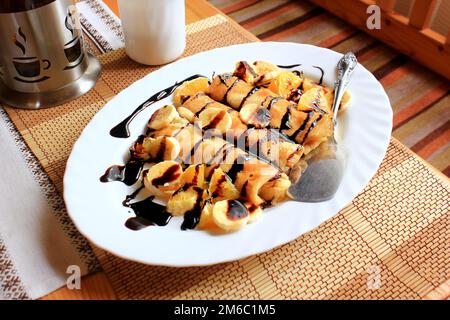 Pfannkuchen gefüllt mit Grieß, Bananen und Orangen getränkt dunklen Schokolade Stockfoto