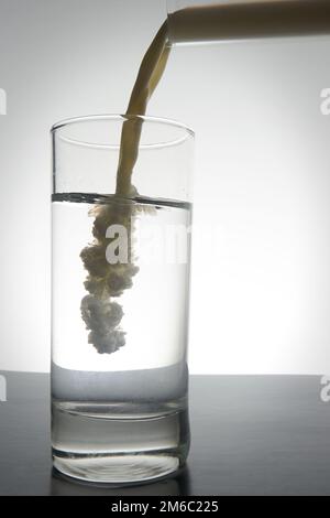 Milch in ein Glas Wasser mit Kopierraum gegossen Stockfoto