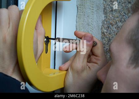 Einbrecher mit Lockpick Werkzeug öffnet die vordere Klappe, um das Haus zu betreten. Auch Schlüsseldienst oder Schlosser Stockfoto