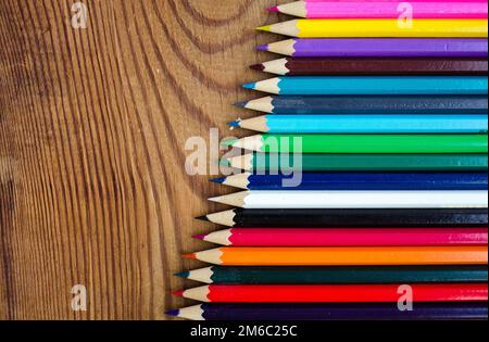 Farbige Bleistifte auf einem Holzbrettgrund Stockfoto