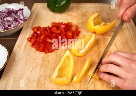 Hände des Mannes schneiden Paprika in der Küche eine Mahlzeit zuzubereiten, für das Mittagessen. Stockfoto