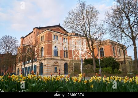 Bayreuth Wagner Festspielhaus in den Sonnenuntergang mit Frühlingsblumen im Vordergrund. Stockfoto