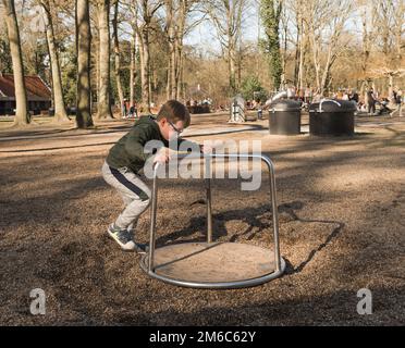 Ein Junge reitet auf einem einfachen Karussell im Herbstpark. Freizeit aus der Schule Stockfoto