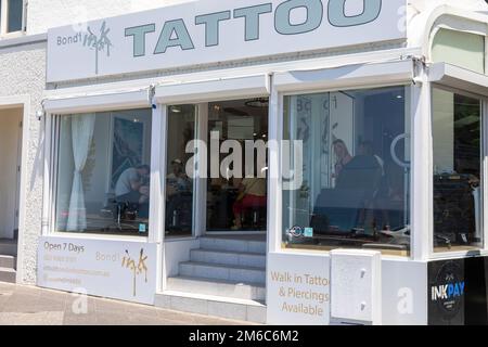 Bondi Beach Ink Tattoo Shop mit Leuten, die Tätowierungen auf ihren Körper angebracht haben, Bondi, Sydney, NSW, Australien Stockfoto