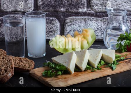 Türkisches Raki mit Wasser auf dem Tisch mit Melonenscheiben und Vorspeise, traditioneller türkischer Alkohol, bekannt als Raki, Chill mit Freunden im Restaurant, Abendessen Stockfoto