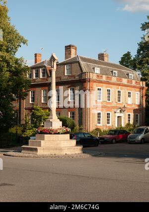 Ein Kriegsdenkmal vor einem Herrensitz in dedham mit einigen geparkten Autos im Sommerlicht Stockfoto