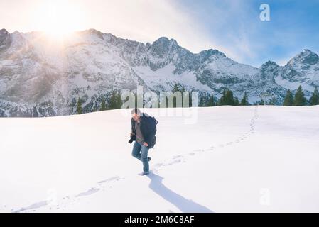 Mann zu Fuß durch Schnee in den Bergen Stockfoto