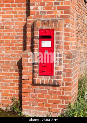 Nahaufnahme des roten königlichen Briefkastens in Backsteinmauern Stockfoto