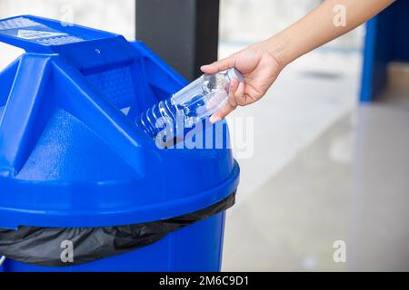 Eine Frau, die leere Flaschen in den Müll wirft Stockfoto