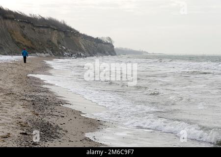 Steile Küste von Ahrenshoop mit turbulenter Ostsee. Ein Mann geht am Ufer entlang. Fischland-Darß-Zingst, Mecklenburg-Vorpommern, Deutschland Stockfoto