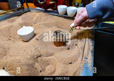 Türkischer Kaffee im Sand zubereitet, türkischer Kaffee vom Straßenverkäufer zubereitet Stockfoto