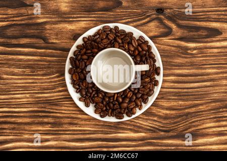 Auf der Untertasse befindet sich eine leere Tasse für Kaffee und Liege Kaffeebohnen Stockfoto