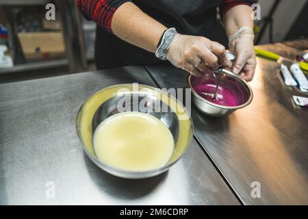 Lebensmittelfärbung bei der Zubereitung von Buttercremevereisung. Professionelle Konditorküche. Rosa Glasur. . Hochwertiges Foto Stockfoto