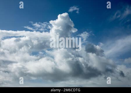 Dramatische Wolken im Sonnenlicht gegen den blauen Himmel. Stockfoto