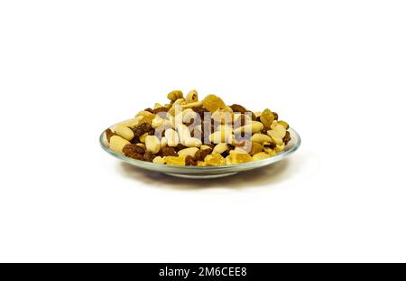 Mischung aus Nüssen, Rosinen und kandierten Früchten auf einer Untertasse mit weißem Hintergrund Stockfoto