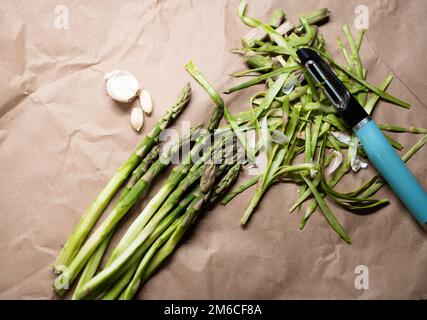 Ein Haufen grün geschälter Spargel mit Knoblauch auf dem Tisch Stockfoto