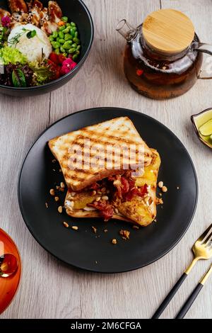 Sandwich mit Speck, Ei, Nüssen auf einem Teller Stockfoto